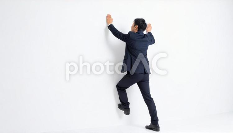 白い壁にのぼって乗り越える日本人男性 壁,乗り越え,男性の写真素材