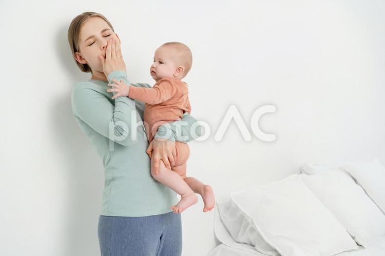 あくびをしながら赤ちゃんを抱く女性 女性,赤ちゃん,かわいいの写真素材