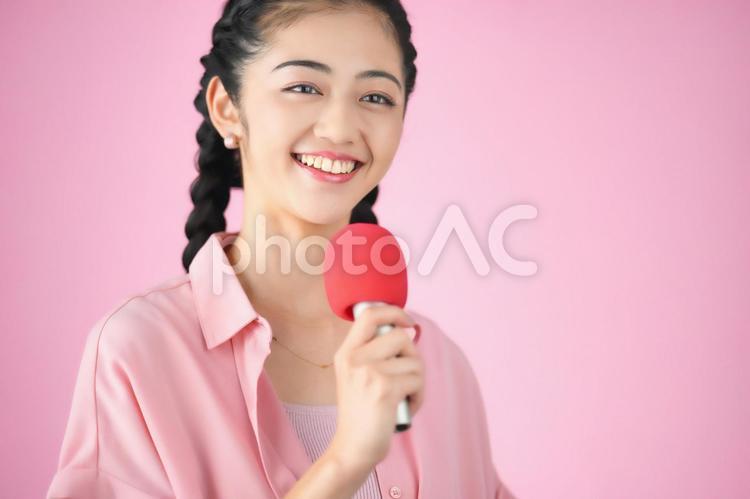 ピンク背景でマイクを持っている女性 女性,日本人,ポートレートの写真素材