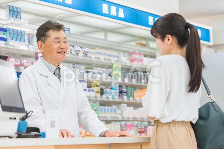 ドラッグストアで働く薬剤師と相談する客 薬剤師,相談,薬局の写真素材