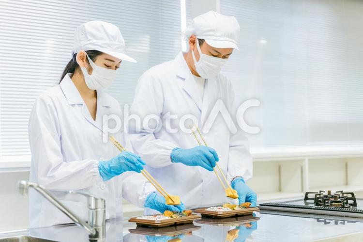 お弁当の盛り付けをする男女（食品加工） 食品工場,社員食堂,食品加工の写真素材