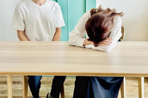 落ち込む女性と横に座る男性 落ち込む女性と横に座る男性の写真