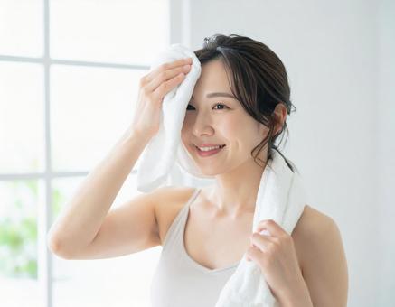 トレーニング後の汗を拭く笑顔の女性 トレーニング後の汗を拭く笑顔の女性の写真