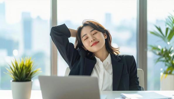 仕事が終わり達成感で背伸びをする社員 仕事が終わり達成感で背伸びをする社員の写真
