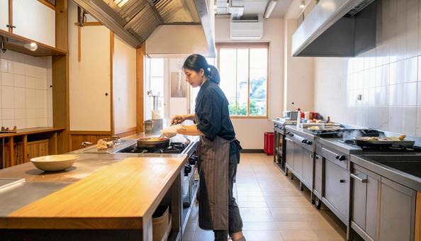 レストランの調理場で料理するスタッフ女性 レストランの調理場で料理するスタッフ女性の写真