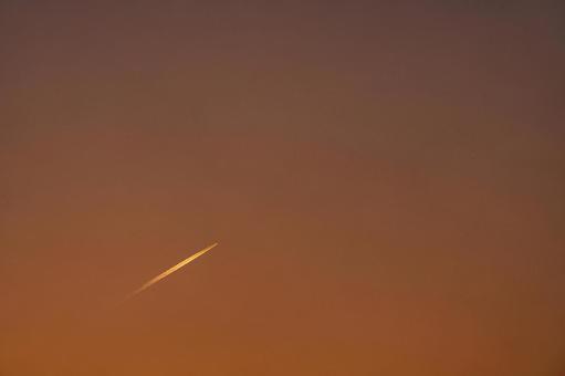 夕焼けに染まる空を飛んでいく飛行機雲 夕焼け,夕暮れ,夕方の写真素材