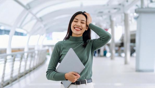 ノートパソコンを持つ笑顔の女性の写真