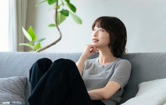 リビングのソファに座る笑顔の女性 リビングのソファに座る笑顔の女性 女性,ソファ,微笑むの写真素材