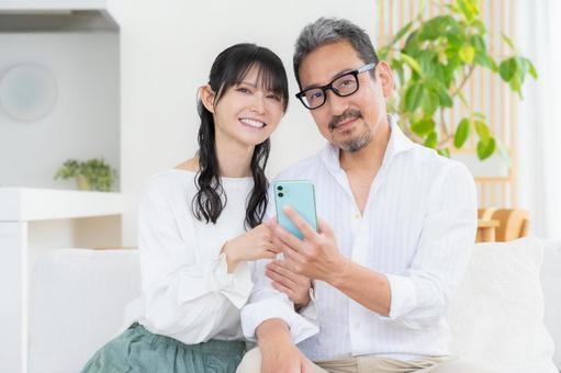 リビングでスマホを見るミドルの夫婦 リビングでスマホを見るミドルの夫婦 夫婦,家族,ミドルの写真素材