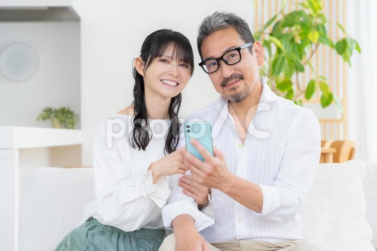リビングでスマホを見るミドルの夫婦 リビングでスマホを見るミドルの夫婦 夫婦,家族,ミドルの写真素材