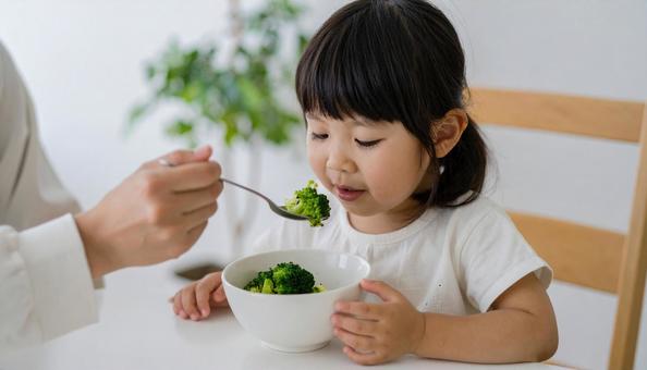 苦手な野菜を食べる女の子 苦手な野菜を食べる女の子の写真