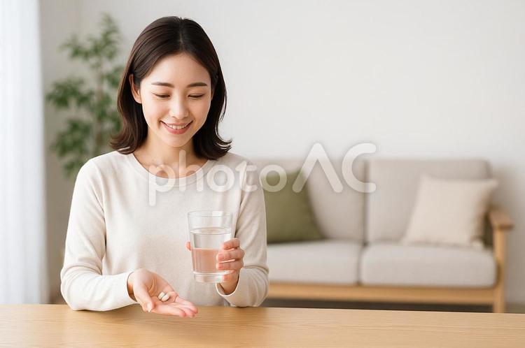 薬と水の入ったコップを持つ女性 女性,女,リラックスの写真素材