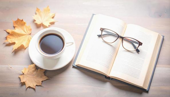 読書の秋イメージ　コーヒーと本・メガネの写真