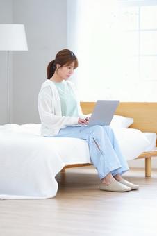 ベッドに座りパソコン操作する女性 女性,ノートパソコン,座るの写真素材