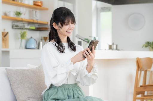 リビングでスマホを見るミドルの女性 リビングでスマホを見るミドルの女性 女性,ミドル,スマホの写真素材