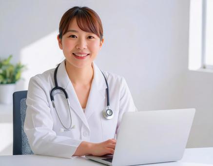診察室でパソコンを操作する白衣の女性医師 診察室でパソコンを操作する白衣の女性医師の写真