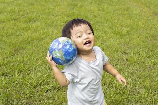 地球儀を持って草原で立っている男の子 男の子,地球,地球儀の写真素材