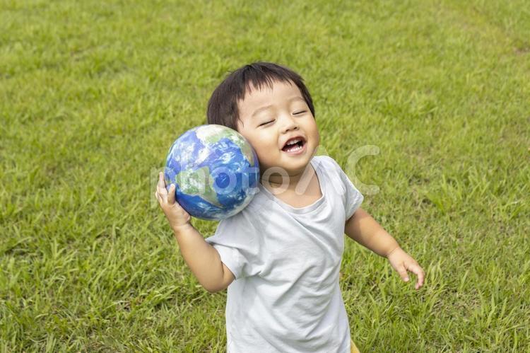 地球儀を持って草原で立っている男の子 男の子,地球,地球儀の写真素材