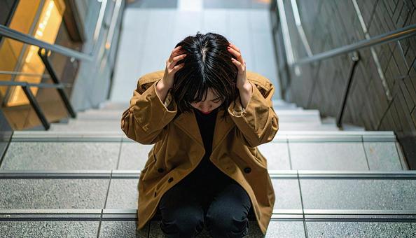 頭を抱えて落ち込む日本人女性の写真