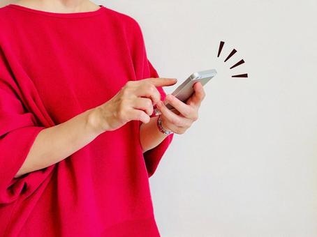 スマホを操作する赤い服の女性 スマホを操作する赤い服の女性 スマホ,女性,操作の写真素材