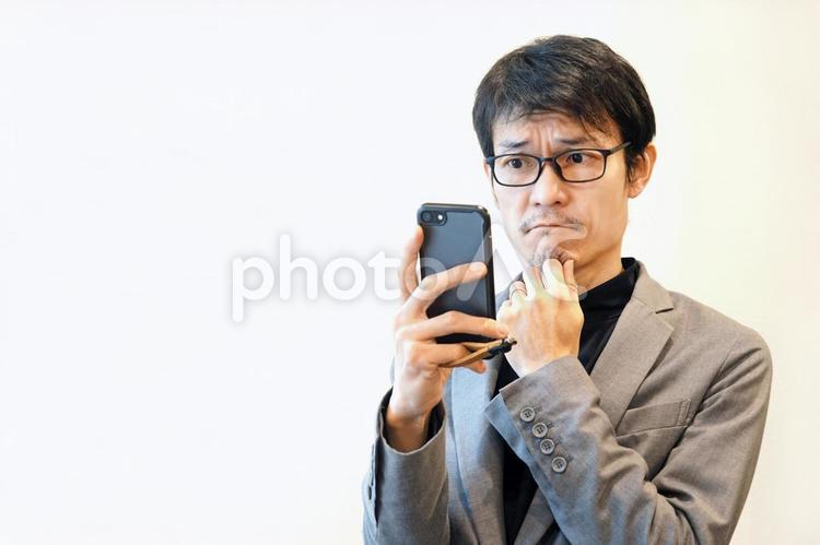 スマホを見て悩むビジネスマン ビジネスマン,男性,携帯の写真素材