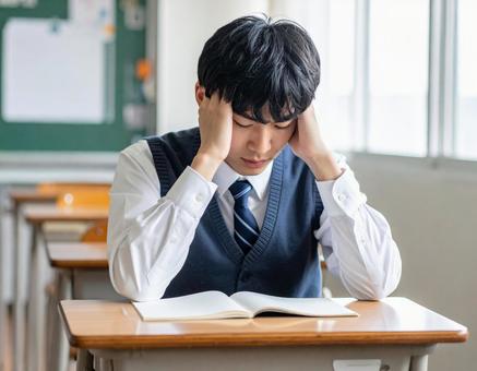 授業中に頭を抱えて悩む男子学生 授業中に頭を抱えて悩む男子学生の写真