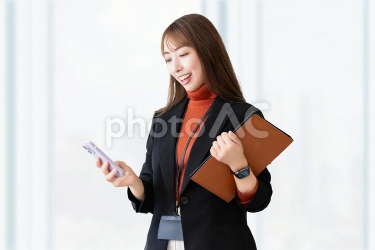 スマホとバインダーを持つ笑顔の女性 女性,スマホ,笑顔の写真素材