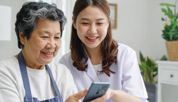 見守り訪問 スマホを使う高齢者とスタッフ 見守り訪問 スマホを使う高齢者とスタッフの写真