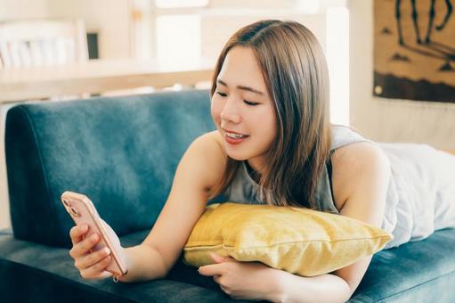 リビングでくつろぎながらスマホを使う女性 リビングでくつろぎながらスマホを使う女性 スマホ女性,スマホ,女性の写真素材