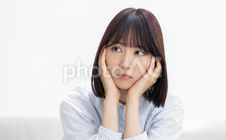 両手で頬を押さえて考えるビジネスウーマン 女性,ビジネス,ビジネスウーマンの写真素材