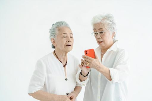 Senior women operating smartphones through trial and error Senior women operating smartphones through trial and error