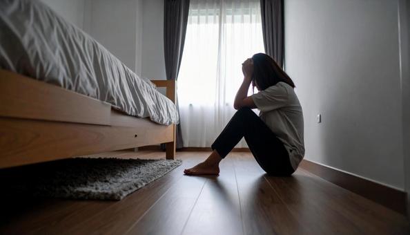 部屋で一人落ち込む女性 部屋で一人落ち込む女性の写真