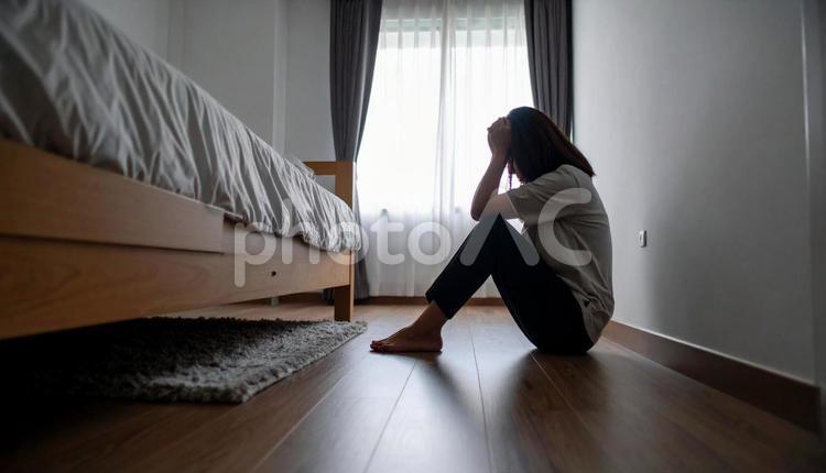 部屋で一人落ち込む女性 悩む,女性,暗いの写真素材
