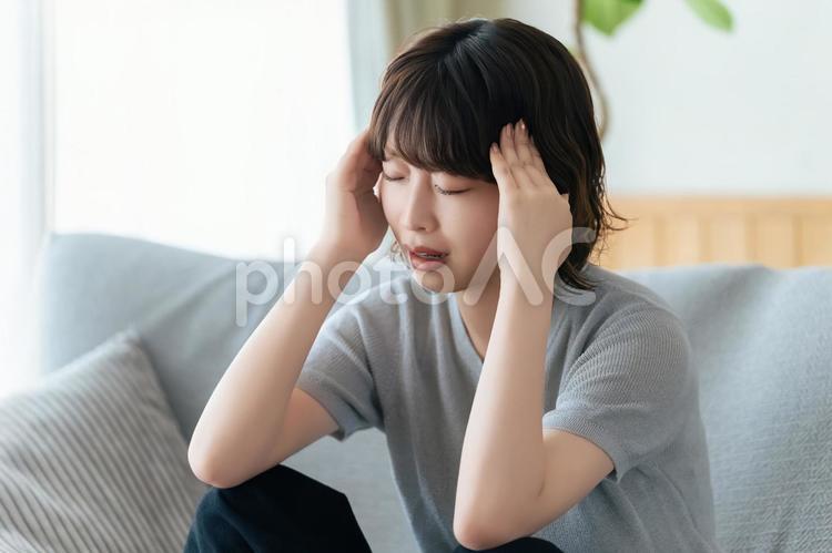 頭を押さえて悩む女性 女性,悩む,困るの写真素材
