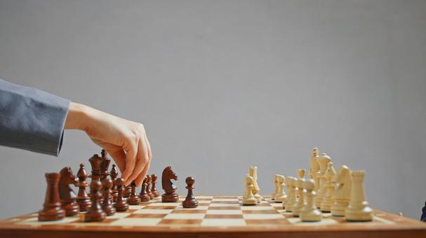 チェスをしている横向きのスーツを着た女性の手（グレー背景） チェス,女性,30代の写真素材