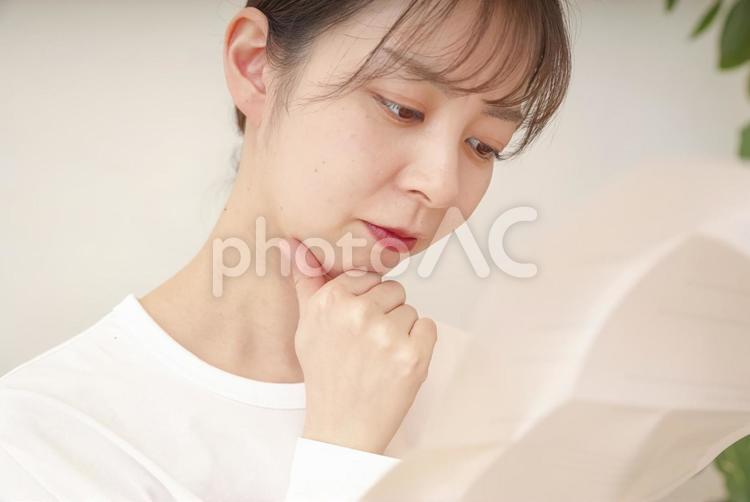 書類を見て複雑な表情をする女性 請求書,催告書,督促状の写真素材