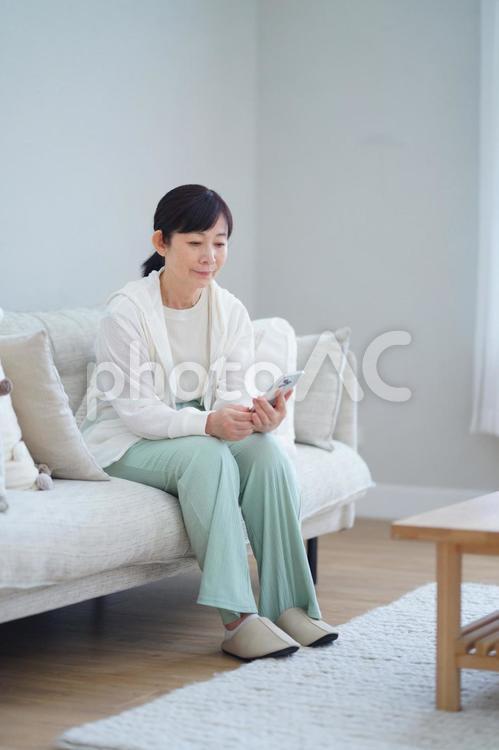 スマートフォンを見ながらくつろぐ中年女性 主婦,シニア,中年の写真素材