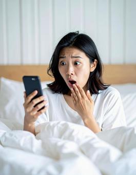 スマホを見て驚く女性のリアクション スマホを見て驚く女性のリアクションの写真