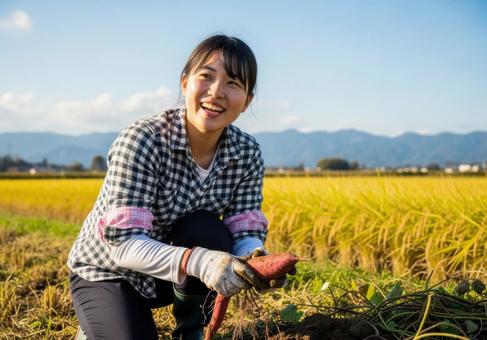 さつまいもを手に笑顔の女性の収穫風景 さつまいもを手に笑顔の女性の収穫風景の写真