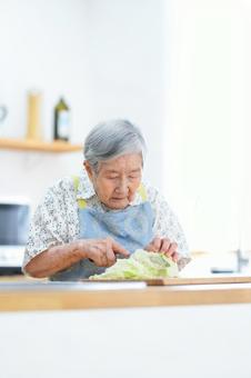 真剣な顔で野菜を切っている高齢女性 女性,キャベツ,包丁の写真素材