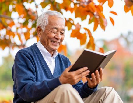 秋の紅葉の下で読書する高齢男性 秋の紅葉の下で読書する高齢男性の写真