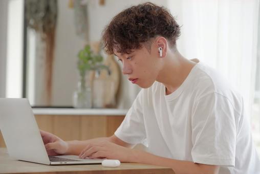 リビングでパソコン作業をする若い男性 考える,悩む,真剣の写真素材