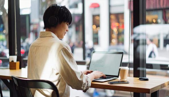 カフェで仕事をするフリーランス男性 カフェで仕事をするフリーランス男性の写真