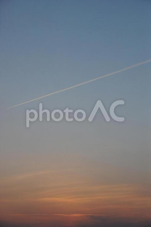 地平線に沈むきれいな夕日と飛行機雲 夕日,夕焼,飛行機雲の写真素材