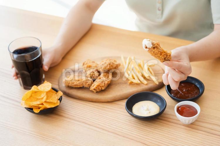 フライドチキンと飲み物を持つ人の手元 手元,女性,人物の写真素材