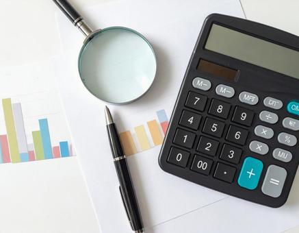 Aerial view of a desk with bar graph data and a magnifying glass, investment, asset, savings, JPG