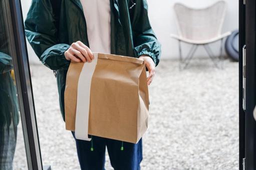 料理の入った紙袋を届けに来た配達員 配達,フードデリバリー,デリバリーの写真素材