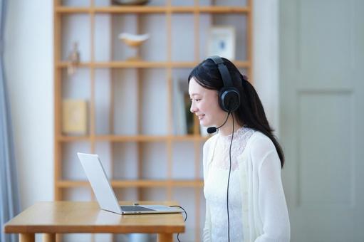 微笑みパソコンを見つめるヘッドセットの女性 女性,ノートパソコン,笑顔の写真素材