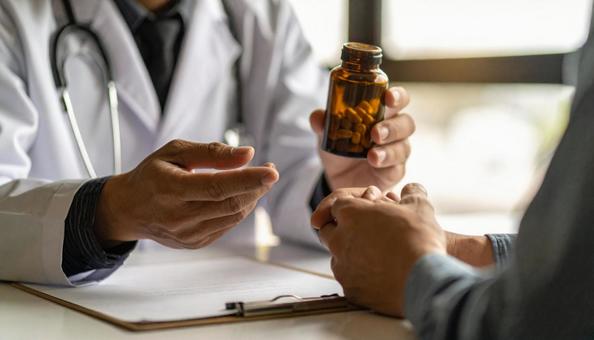 患者に対して簡単な服薬指導を行う男性医師 患者に対して簡単な服薬指導を行う男性医師の写真