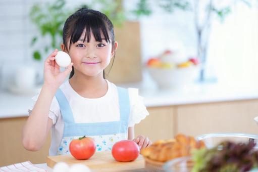 材料を前にキッチンで卵を手に持つ子どもの笑顔 女の子,小学生,日本人の写真素材